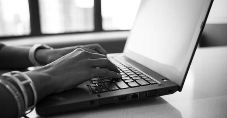 Fotografi Grayscale Seorang Wanita Yang Bekerja Di Depan Laptop