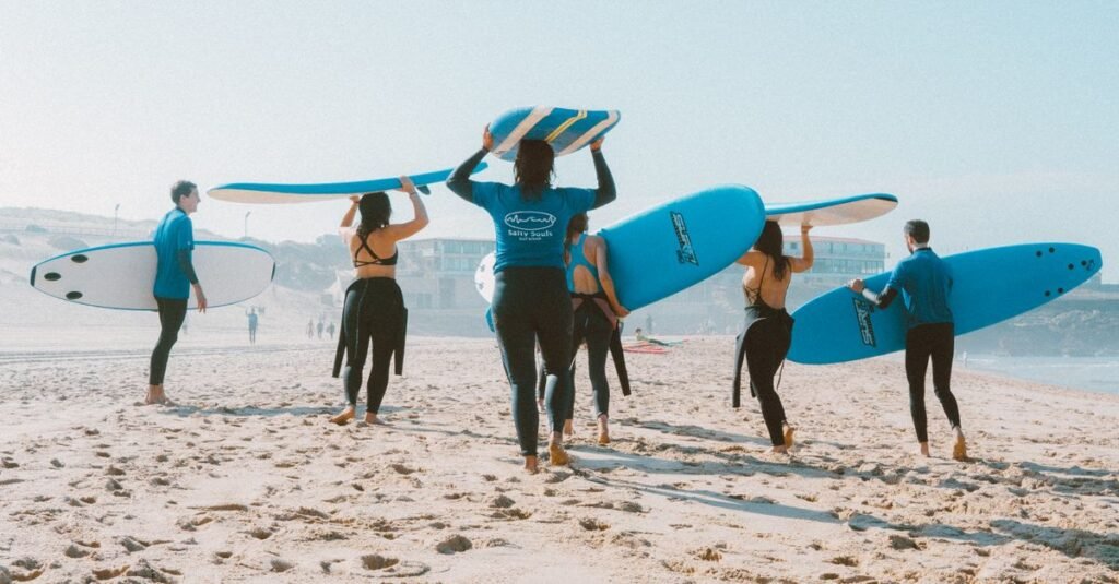 Group of surfers with blue surfboards heading to the ocean on a sunny beach.
