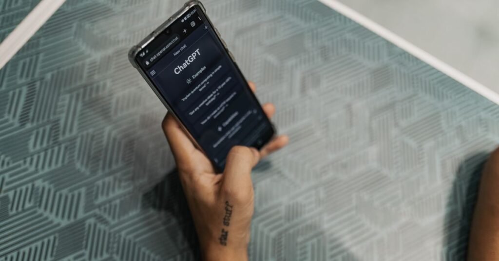 Close-up of a person holding a smartphone displaying the ChatGPT application interface on a patterned table.