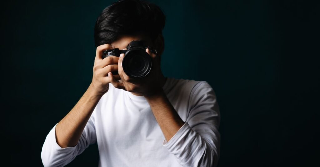 Potret seorang fotografer muda dalam suasana studio sambil memegang kamera.