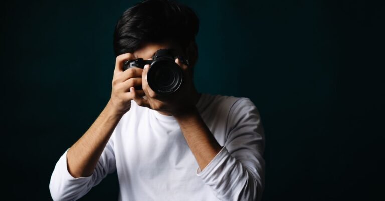 Potret seorang fotografer muda dalam suasana studio sambil memegang kamera.