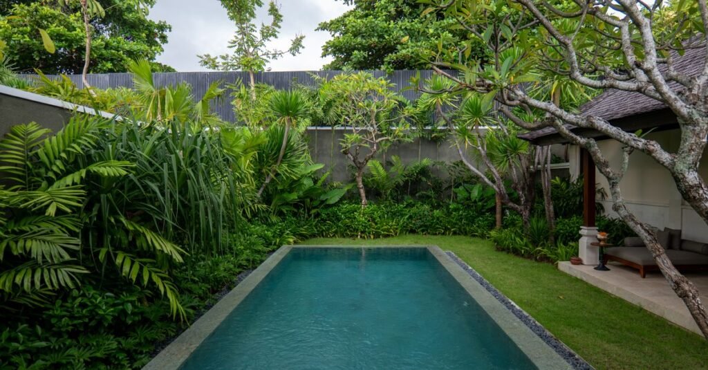 Vila mewah dengan kolam renang yang dikelilingi oleh tanaman tropis yang rimbun di Bali, Indonesia.