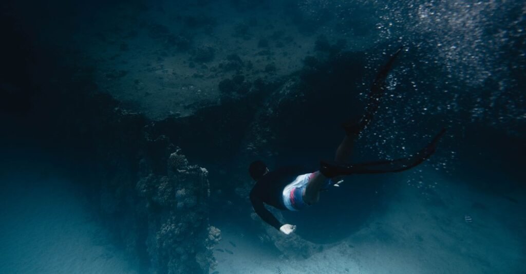 A diver swims gracefully through a vibrant coral reef underwater, captured in motion.