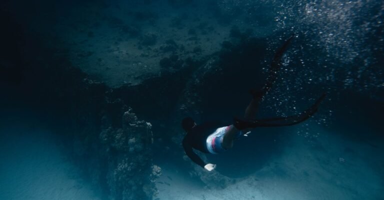 A diver swims gracefully through a vibrant coral reef underwater, captured in motion.