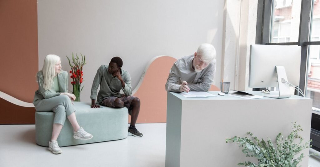 Full body of multiethnic coworkers sitting on sofa and writing on paper while working together in contemporary office with computer
